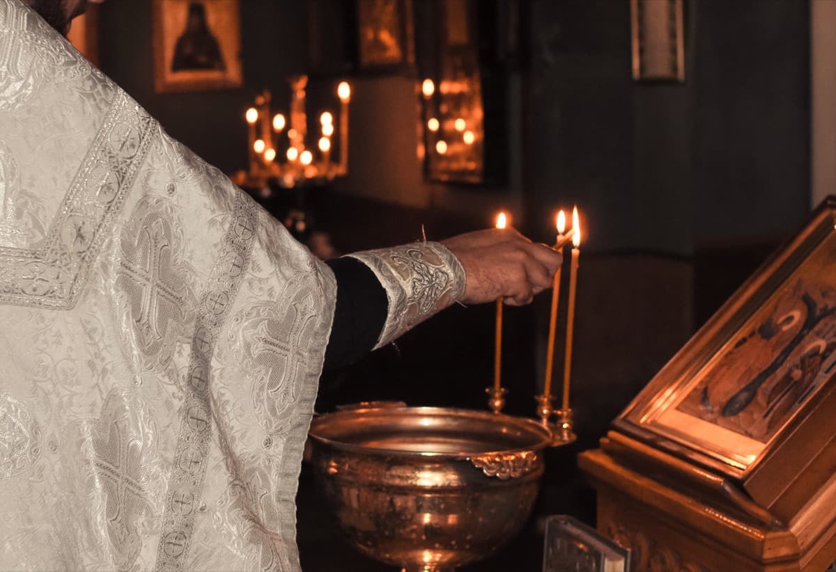Priest lighting candles in church for christening ceremony