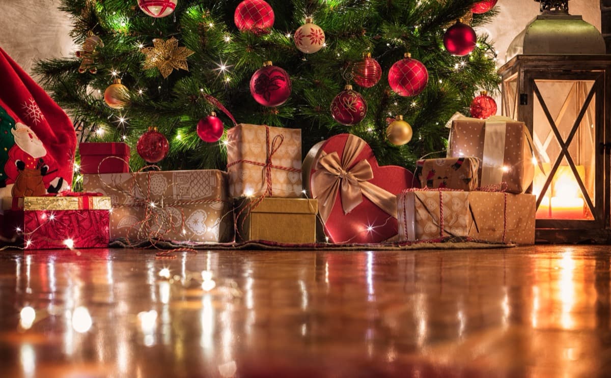 Beautifully wrapped Christmas gifts under a decorated tree with festive lights