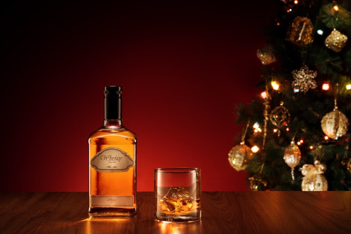 Whisky bottle and glass with Christmas tree in background