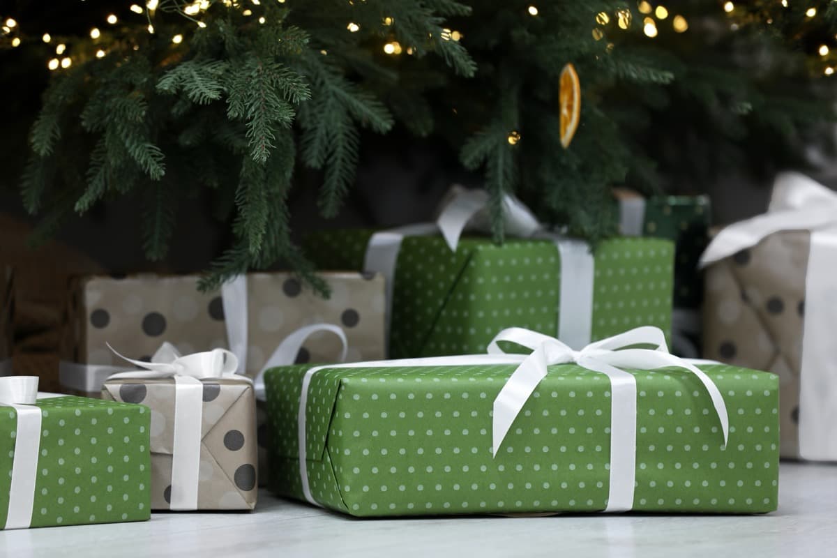 Green wrapped Christmas presents under decorated tree