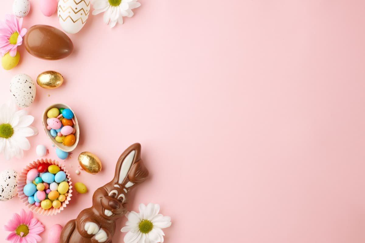 Chocolate Easter bunny with pastel eggs on pink background