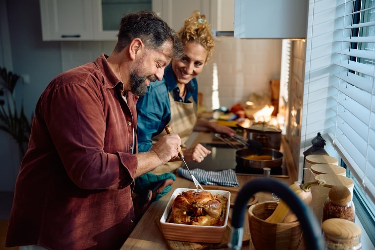 Happy couple cooking together in kitchen preparing a meal