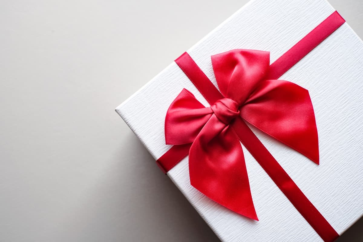 A single wrapped gift with a red ribbon on a plain background