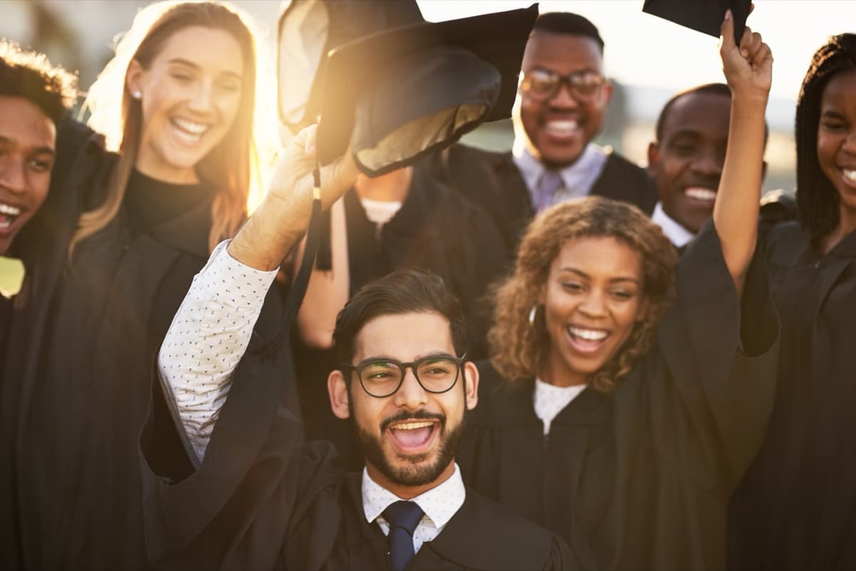 Graduates celebrating in caps and gowns throwing hats in the air