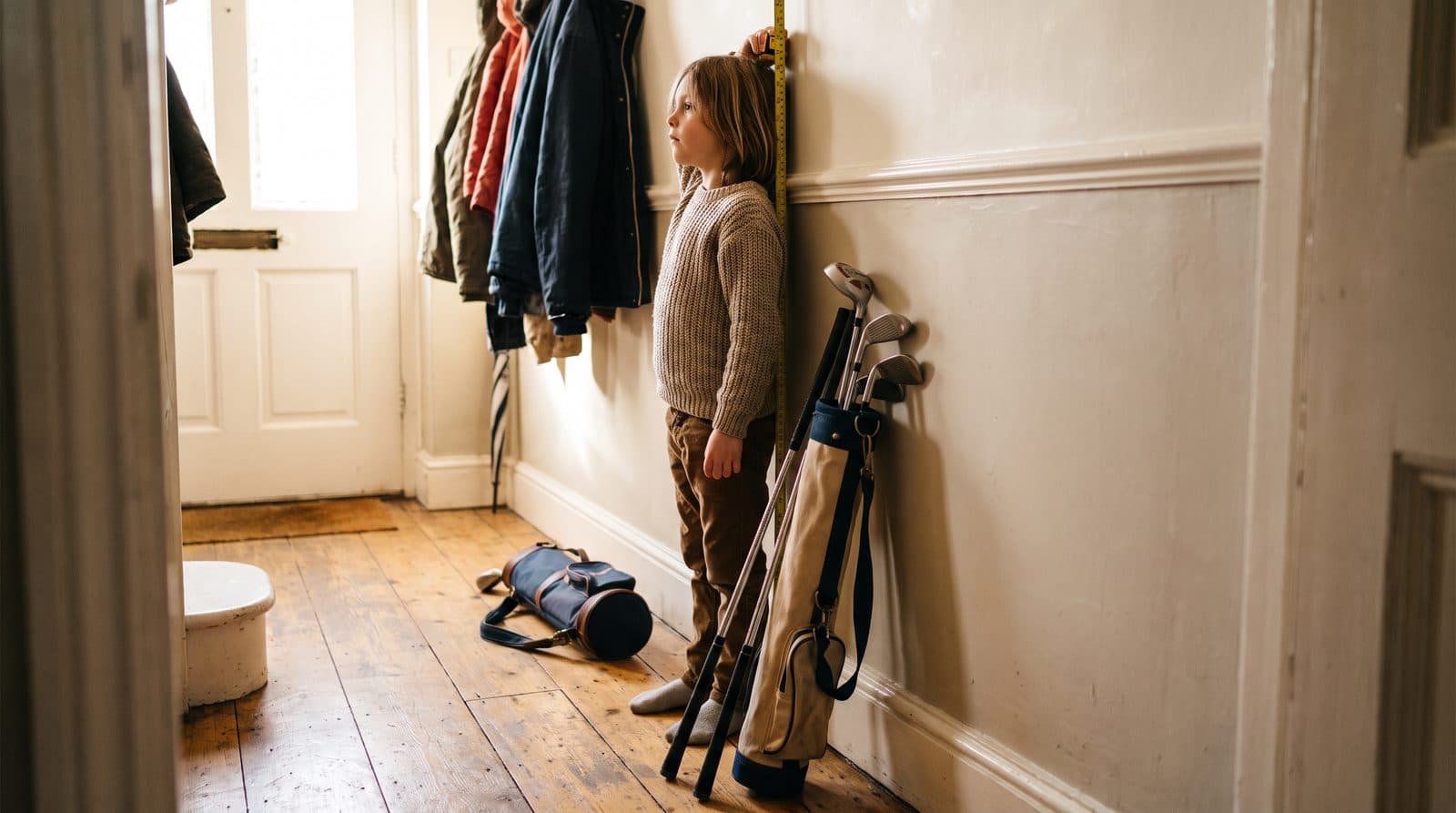 Junior golfer measured against a set of golf clubs on a practice green