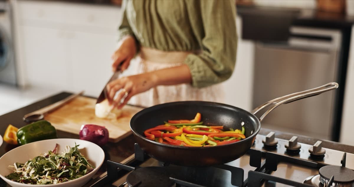 Woman cooking in kitchen with wok preparing a fresh stir fry meal