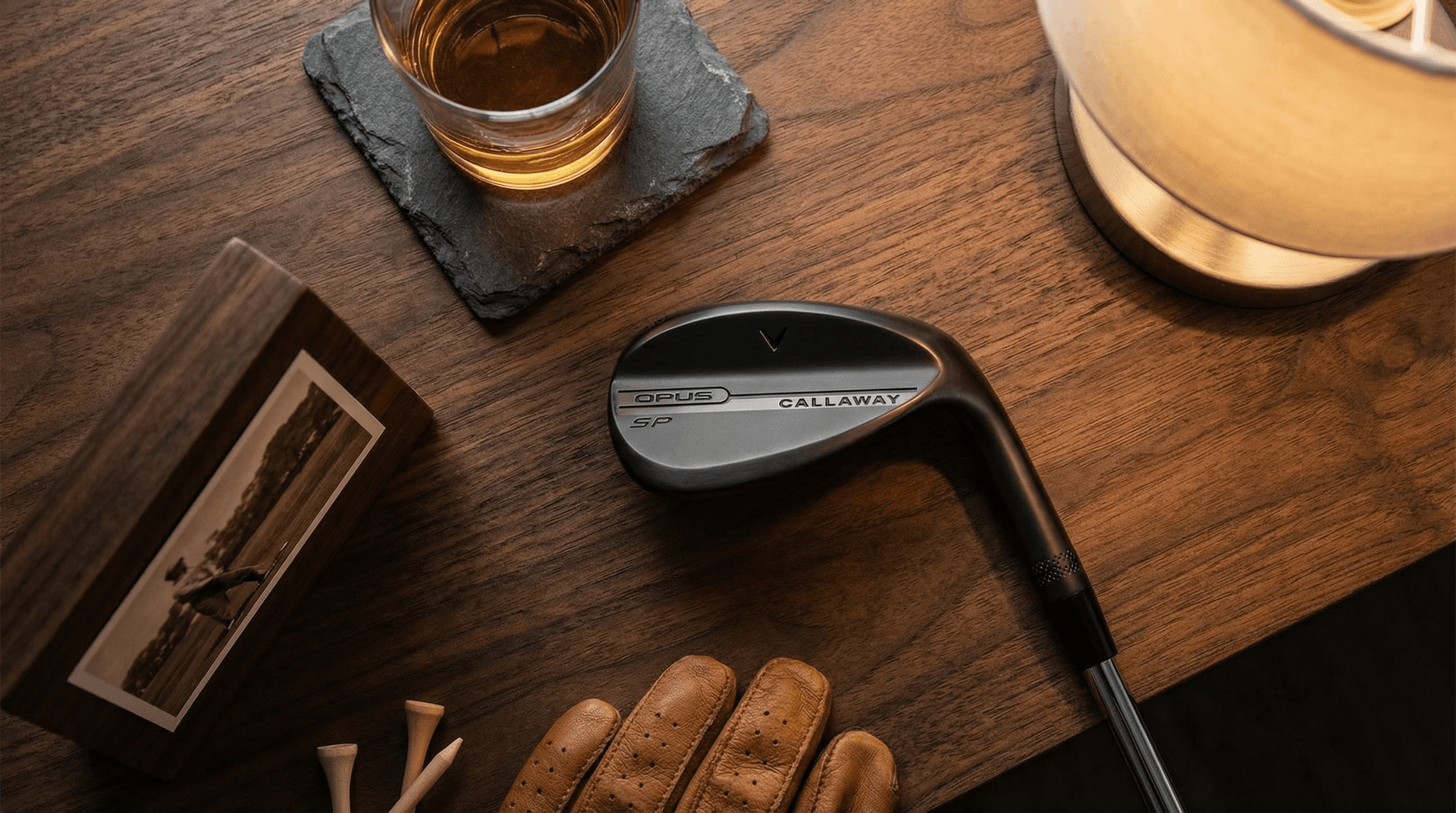 Selection of personalised gifts for men including an engraved golf wedge, photo block, and slate coasters on a dark wood surface