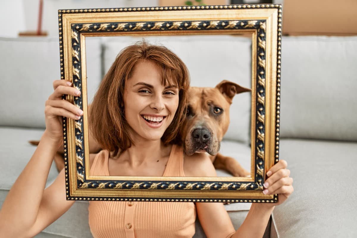 Woman holding her dog in picture frame for pet lover gift