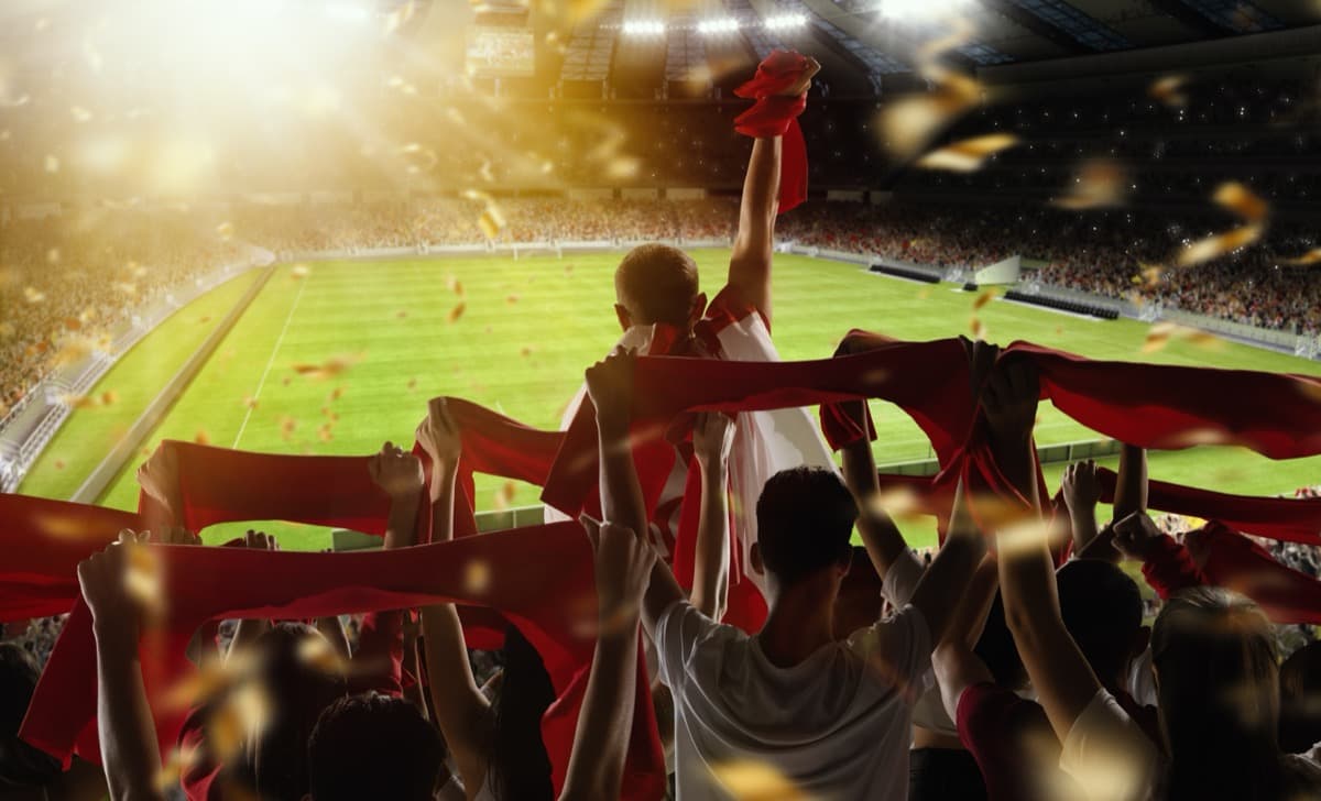Football fans cheering in stadium with red scarves
