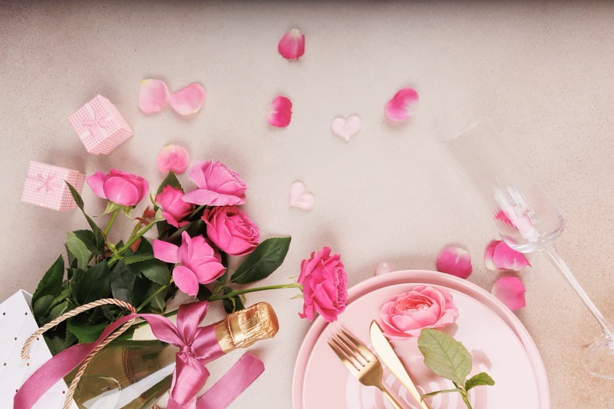 Romantic Valentine's Day table setting with pink roses champagne glasses and elegant place settings