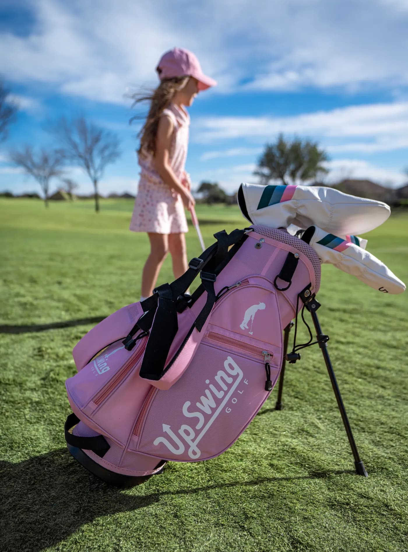 Pink Upswing junior stand bag on the fairway with a young golfer walking behind it