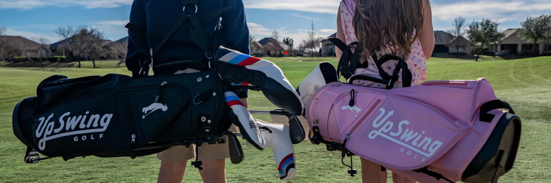 Two junior golfers walking a fairway carrying Upswing golf bags